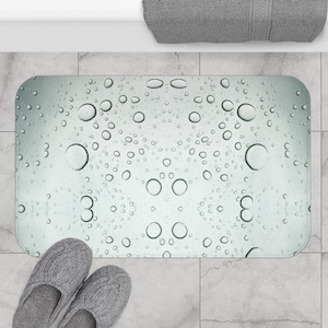 May include: A light green bath mat with a pattern of water droplets. The mat is made of a soft, absorbent material and is perfect for keeping your bathroom floor dry.