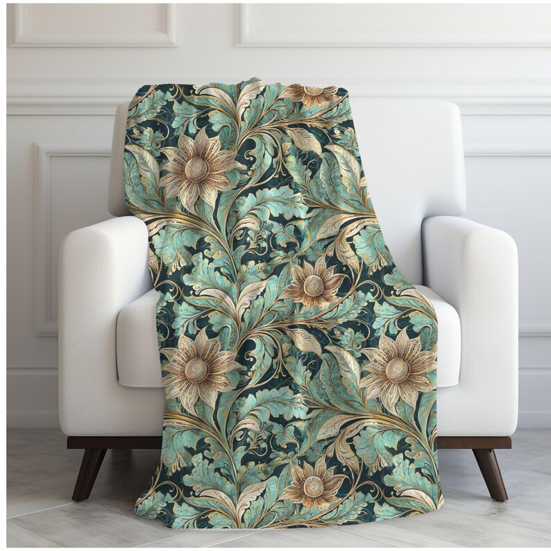 May include: A teal and gold floral throw blanket with a repeating pattern of stylized flowers and leaves. The blanket is draped over a white armchair.