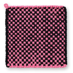 May include: Square, woven hot pad in a checkerboard pattern of black and pink. The edges are trimmed with a black and pink border. A small loop is attached to one corner.