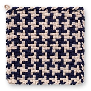 May include: Square woven pot holder in navy blue and beige. The pot holder features a geometric pattern and a loop for hanging. The edges are finished with a braided trim. A kitchen accessory.