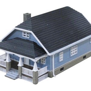 Könnte beinhalten: Ein blaues und weißes Modellhaus mit einer Veranda und einem schwarzen Dach. Das Haus hat einen Schornstein und mehrere Fenster.