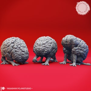 May include: Three gray brain-shaped sculptures with legs are displayed against a red background. The sculptures are detailed, with visible folds and ridges. The sculptures are in different poses, with one appearing to walk.