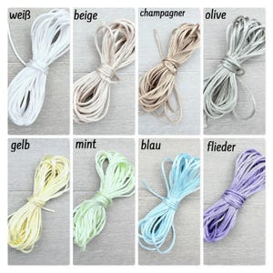 Könnte beinhalten: Eine Sammlung von acht aufgewickelten Schnüren in verschiedenen Farben, darunter weiß, beige, champagner, olive, gelb, mint, blau und flieder. Jede Schnur ist ordentlich gebündelt und mit dem entsprechenden Farbnamen in Textform beschriftet.
