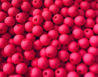 May include: A close-up shot of a pile of bright red, round beads. Each bead has a hole running through the center. The beads are evenly colored and appear to be made of a smooth material. The beads are likely used for jewelry making or crafts.