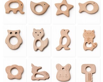 May include: A collection of twelve wooden baby teethers in various shapes, including an elephant, bird, star, fish, owl, fox, penguin, raccoon, flower, deer, bunny, and key. Each teether is made of light-colored wood and features a hole for easy gripping.