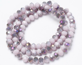 May include: A strand of round, faceted glass beads in a soft, pale lavender color. Each bead features a polished, reflective surface with subtle iridescent highlights that catch the light, arranged in a circular loop on a thin, clear string.