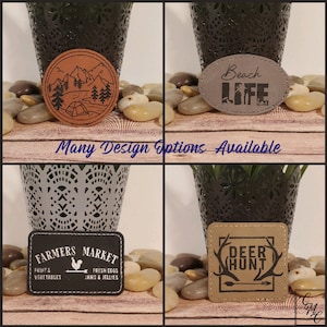 May include: A collage of four leather patches with various designs. One is round with a mountain and tent scene, another oval with "Beach Life", a rectangular one with "Farmers Market", and a square one with "Deer Hunt". The text "Many Design Options Available" is also present.