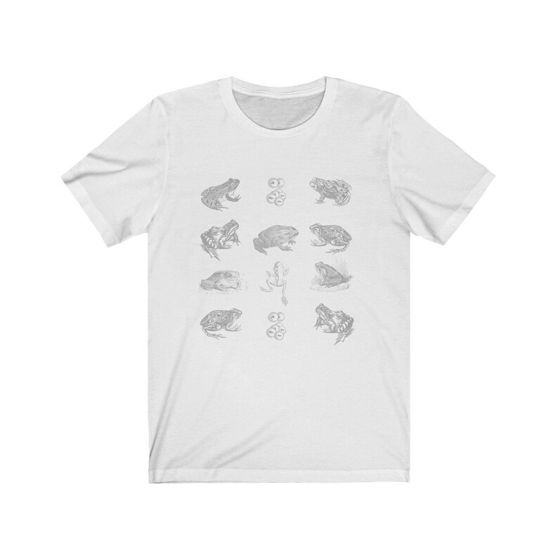 Pode incluir: Camiseta branca com uma ilustra&ccedil;&atilde;o em preto e branco de diferentes sapos e cogumelos.