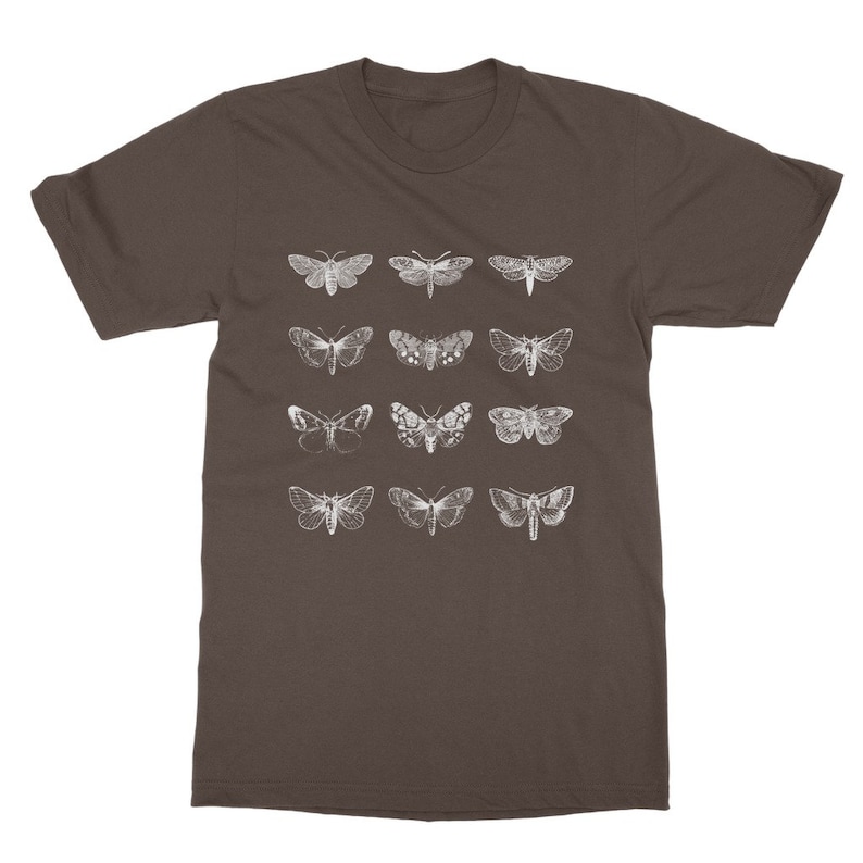 Op de afbeelding: Een bruin t-shirt met een raster van twaalf witte motillustraties. De motten hebben gedetailleerde vleugelpatronen en vari&euml;ren in grootte. Het t-shirt heeft een ronde hals.