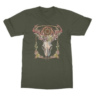 May include: Olive green t-shirt featuring a watercolor design of a skull with antlers, a dreamcatcher, and floral accents. The design is framed with a gold border and botanical elements. The shirt is a classic crew neck style.