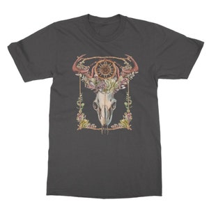 May include: Dark gray t-shirt featuring a watercolor design of a skull with antlers, a dreamcatcher, and floral elements. The design is framed with a gold border and green foliage. A unique graphic tee.