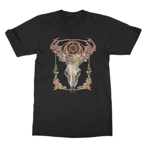 May include: Black t-shirt featuring a watercolor design of a skull with antlers, a dreamcatcher, and floral accents. The design is framed with a gold border. The shirt is a classic crew neck style.