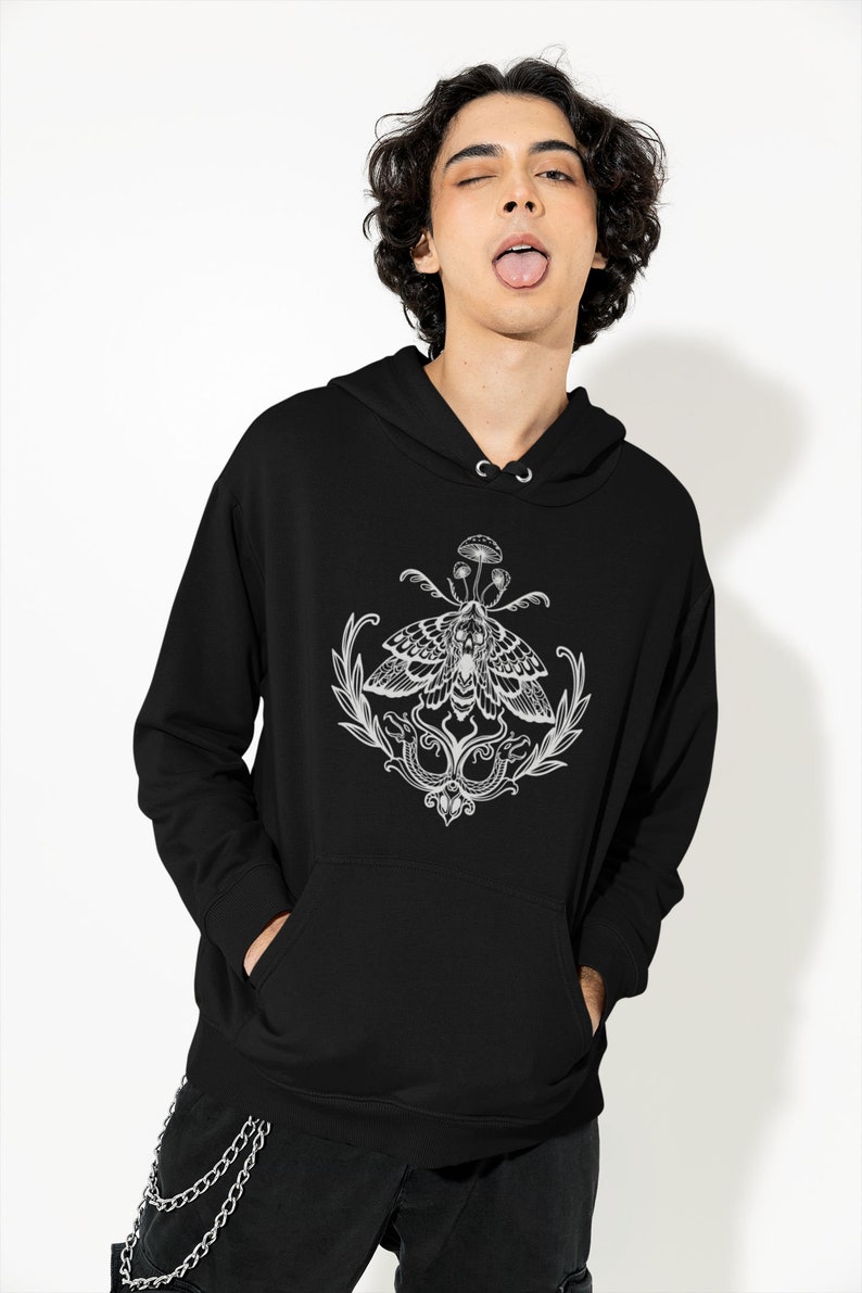 K&ouml;nnte beinhalten: Ein schwarzer Kapuzenpullover mit einem wei&szlig;en Grafikdruck auf der Brust. Das Design zeigt einen Nachtfalter mit einem Totenkopfmuster auf den Fl&uuml;geln, gekr&ouml;nt von einem kleinen Pilz und flankiert von zwei Schlangen und Blattzweigen.