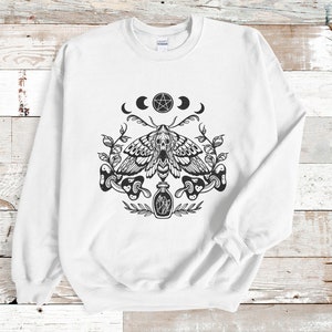 May include: White sweatshirt with a black and white graphic print of a moth, a pentagram, moons, and a bottle. The graphic is centered on the front of the sweatshirt.