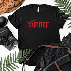 May include: Black t-shirt with the word "Sinner" in red gothic lettering.