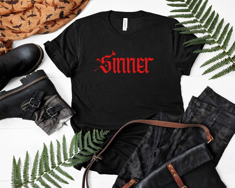 May include: Black t-shirt with the word "Sinner" in red gothic lettering.