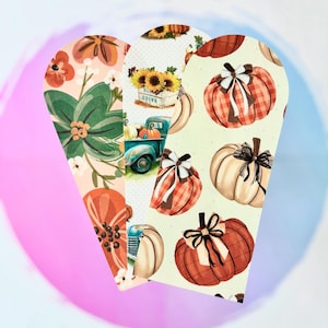 May include: Three decorative, heart-shaped cutouts with fall-themed patterns. One features floral designs, another a vintage truck with pumpkins and sunflowers, and the last showcases pumpkins with bows. The cutouts are set against a gradient background.