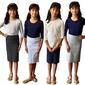 May include: Four girls wearing long-sleeved shirts and knee-length skirts in different colors. The girls are wearing gold sandals and have their hair pulled back.