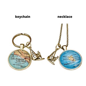 May include: A gold-tone necklace and keychain featuring a sailboat charm and a round pendant with a map of Los Angeles and Honolulu. The necklace has a gold chain and the keychain has a gold ring.
