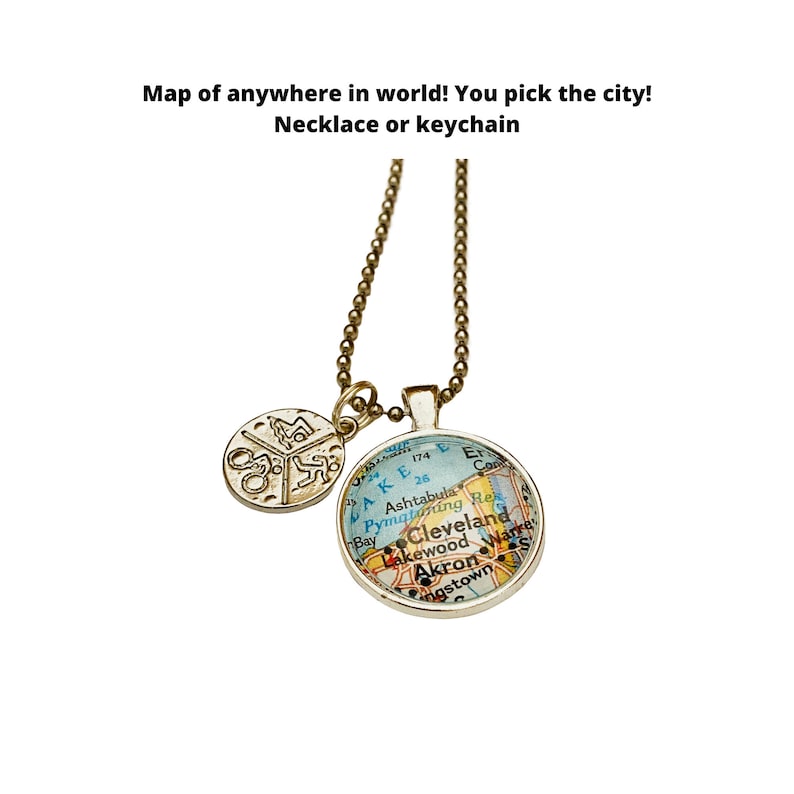 May include: A gold necklace with a round pendant featuring a map of Cleveland, Ohio. The pendant is attached to a gold chain with a smaller round charm.