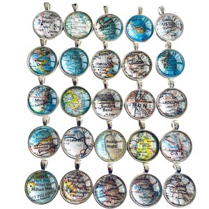 May include: Twenty-four silver charm pendants with glass inserts featuring vintage map designs of various cities around the world. The charms are arranged in four rows of six.