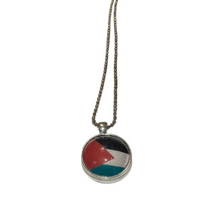 May include: A silver chain necklace with a round pendant featuring the Palestinian flag. The pendant has a red, black, white, and green design.