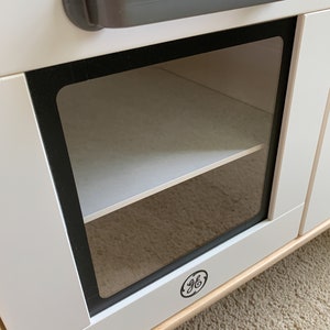 May include: White cabinet with a glass door and a single shelf. The cabinet has a gray handle and a GE logo on the bottom.