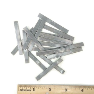 May include: A pile of silver-colored metal strips, likely solder, on a white surface. A ruler is visible in the bottom of the image, with markings from 1 to 5 inches.