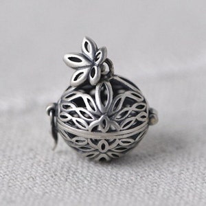 Puede incluir: Un charm de plata con un delicado diseño floral. El charm tiene forma de esfera y tiene una pequeña flor unida a la parte superior. El charm es perfecto para agregar un toque de elegancia a cualquier pieza de joyería.