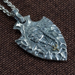 May include: Silver pendant necklace featuring a detailed arrowhead design with a Native American face and a gold accent.