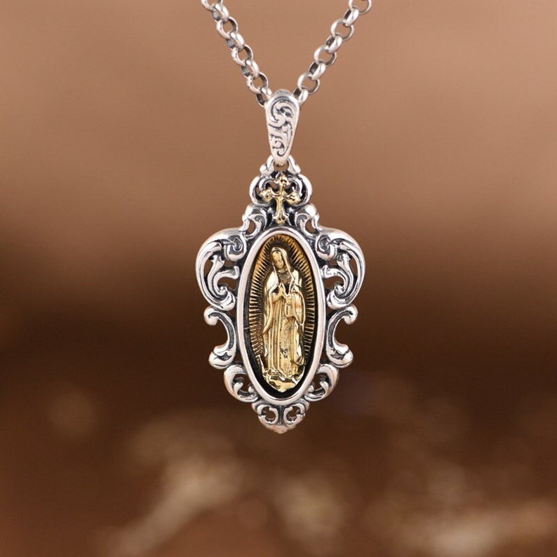 May include: Silver chain necklace with a gold-toned pendant featuring an image of the Virgin Mary in an ornate frame.