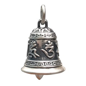 May include: Silver bell charm with intricate designs and the Om symbol. The bell has a loop at the top for hanging.