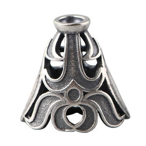 May include: Silver-toned metal pendant cap with an intricate, ornate design. The cap has a conical shape with a wide, flared base and a narrow top.