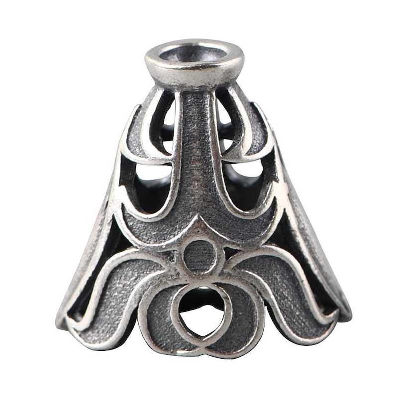 May include: Silver-toned metal pendant cap with an intricate, ornate design. The cap has a conical shape with a wide, flared base and a narrow top.