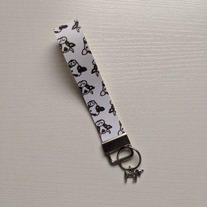 May include: White and black cow print keyring with a silver cow charm.