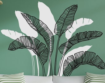 May include: A white couch with green striped throw pillows and a green throw blanket. The wall behind the couch is painted a light green color and features a black and white line drawing of tropical leaves.