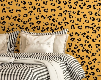 May include: A bed with a black and white striped comforter and pillows. The pillows are white with a button detail. The wall behind the bed is yellow with black leopard print spots. The bed frame is made of wood.