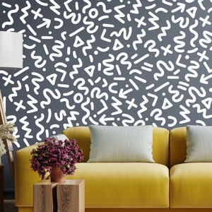 May include: A yellow sofa with two white throw pillows in front of a wall with a white geometric pattern. The pattern is made up of various shapes, including circles, squares, triangles, and wavy lines.