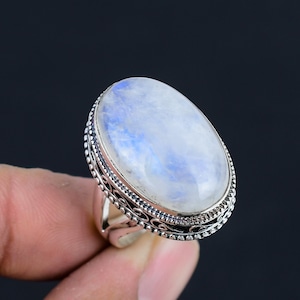 May include: A silver ring with an oval-shaped moonstone. The ring has a detailed silver band with a decorative design.