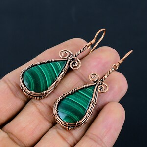May include: A pair of copper wire wrapped earrings with green malachite teardrop shaped stones.