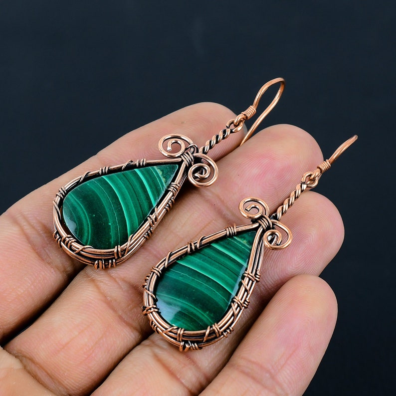 May include: A pair of copper wire wrapped earrings with green malachite teardrop shaped stones.