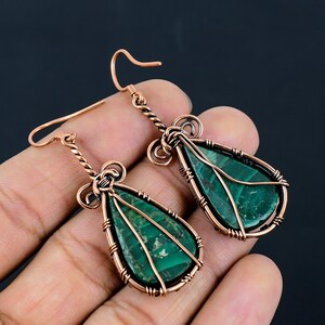 May include: A pair of copper wire wrapped earrings with green malachite stone drops.