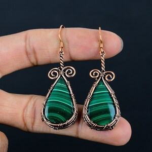 May include: A pair of copper wire wrapped earrings with green malachite teardrop stones.