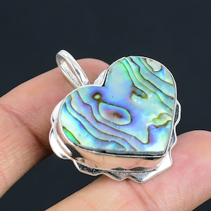 Op de afbeelding: Een zilveren hartvormige hanger met een inleg van blauwe, groene en paarse abalone-schelp.