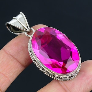 May include: A silver pendant featuring a large, oval-shaped, faceted pink gemstone set in a silver filigree frame.