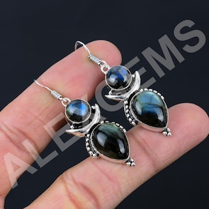 May include: A pair of silver dangle earrings featuring round and teardrop-shaped labradorite gemstones. Each earring has a polished silver setting with decorative beaded accents and a hook-style closure, showcasing the iridescent blue flash.