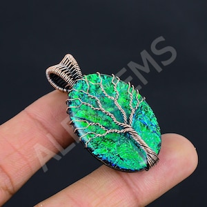 May include: An oval pendant featuring a vibrant green iridescent stone with a textured surface. A copper wire tree design is wrapped over the stone, with the wire extending to form a decorative bail at the top for hanging the piece.
