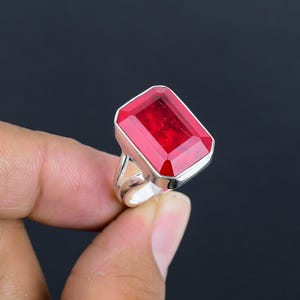 May include: A silver ring with a large, rectangular, red gemstone.