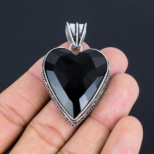 May include: A black heart-shaped pendant with a silver ornate border. The pendant is made of onyx and silver.
