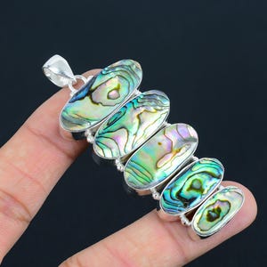 May include: Silver pendant necklace with five oval-shaped abalone shell stones. The stones have iridescent green, blue, and purple colors.
